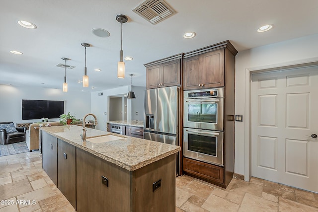 402 E Claremont St, Phoenix, AZ 85012 - kitchen with appliances with stainless steel finishes, stone tile flooring, a sink, open floor plan, and a kitchen island with sink