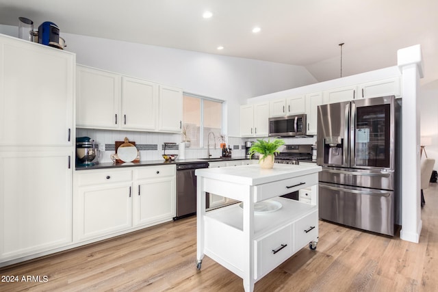 kitchen with light hardwood / wood-style floors, tasteful backsplash, appliances with stainless steel finishes, and vaulted ceiling