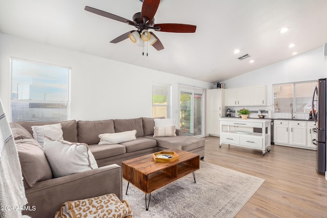 living room featuring light hardwood / wood-style floors, ceiling fan, sink, and vaulted ceiling