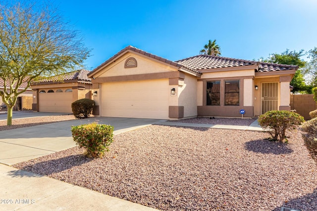 mediterranean / spanish home with driveway, an attached garage, a tile roof, and stucco siding