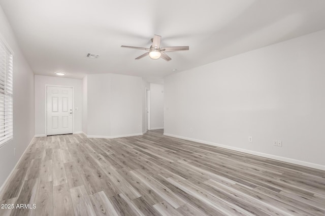 spare room featuring baseboards, ceiling fan, visible vents, and light wood-style floors