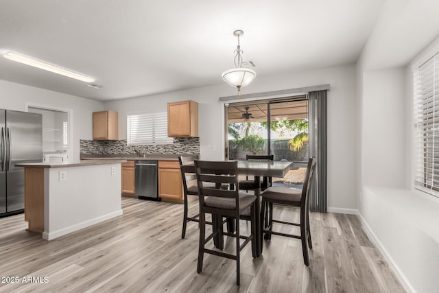 kitchen featuring stainless steel appliances, tasteful backsplash, pendant lighting, light brown cabinetry, and a kitchen island