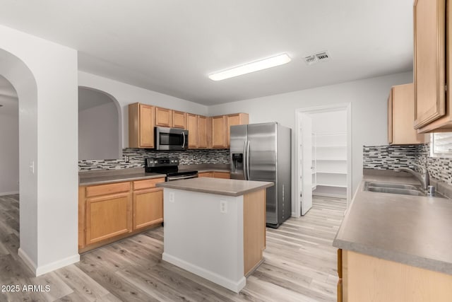 kitchen featuring appliances with stainless steel finishes, light brown cabinetry, sink, a center island, and light hardwood / wood-style floors