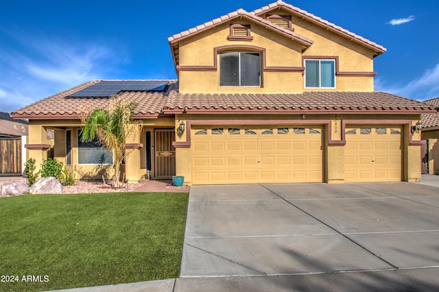 mediterranean / spanish-style home featuring a garage, a front yard, and solar panels