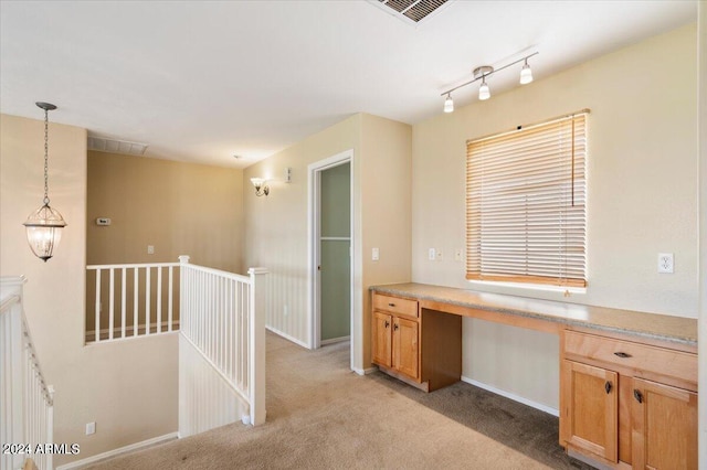 interior space with light carpet, built in desk, and rail lighting