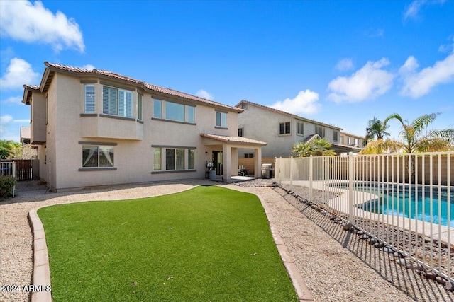 back of house with a patio, a fenced in pool, and a lawn