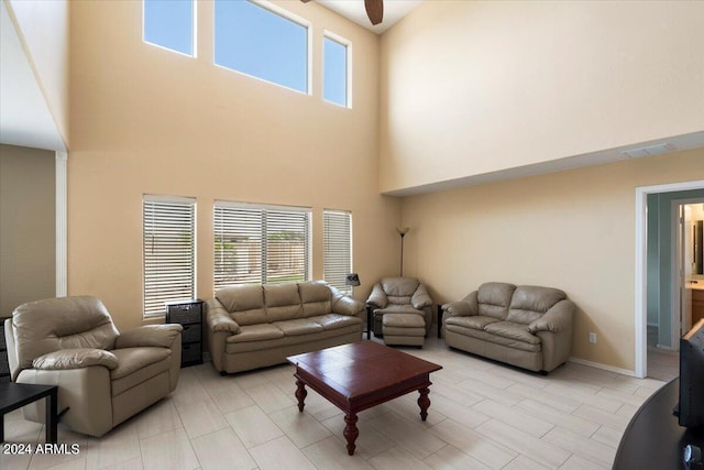 living room with ceiling fan and a towering ceiling