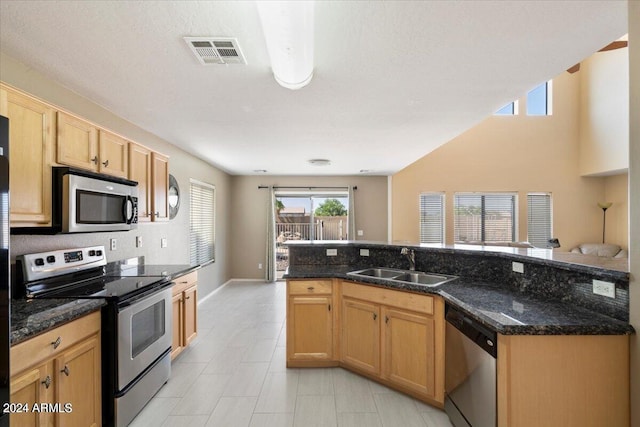 kitchen featuring a textured ceiling, stainless steel appliances, sink, and dark stone counters