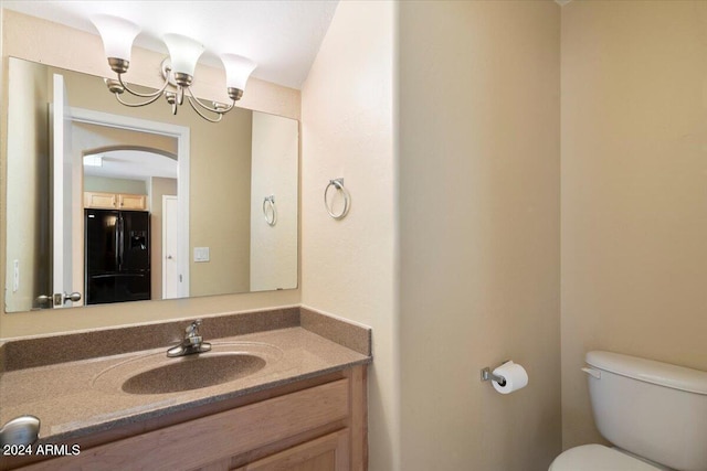 bathroom featuring vanity, toilet, and an inviting chandelier