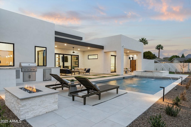 view of swimming pool with an outdoor living space with a fire pit, a patio, an outdoor kitchen, area for grilling, and an in ground hot tub