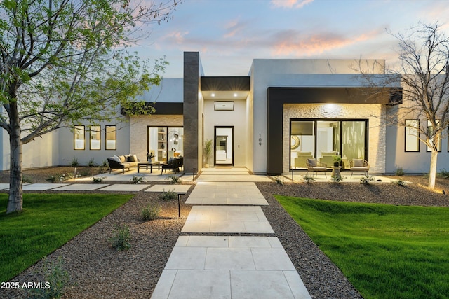 view of front of home featuring a front lawn, an outdoor living space, a patio, and stucco siding