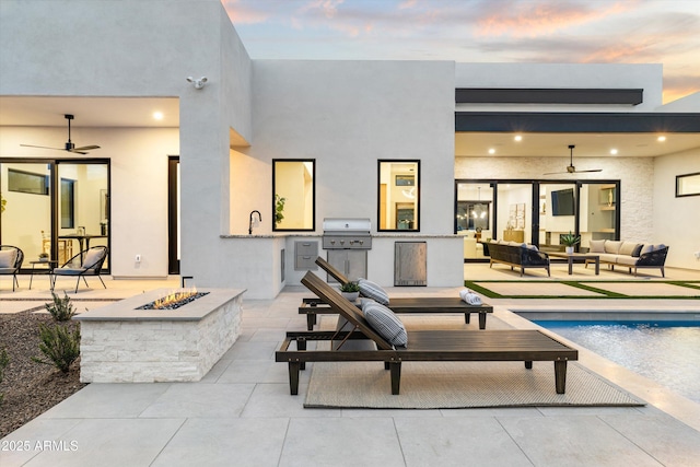 back of house at dusk featuring an outdoor living space with a fire pit, a patio area, area for grilling, and stucco siding