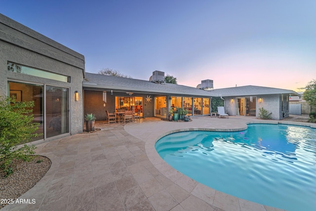 pool at dusk featuring a patio