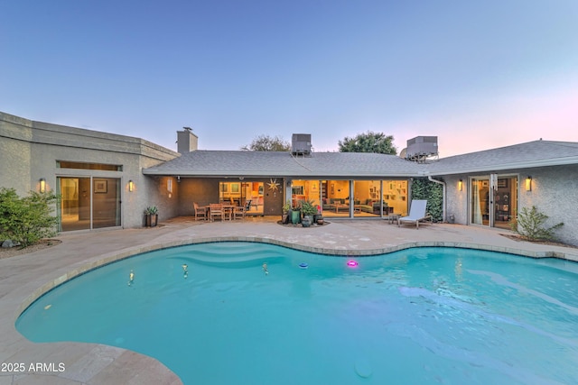 pool at dusk with a patio area