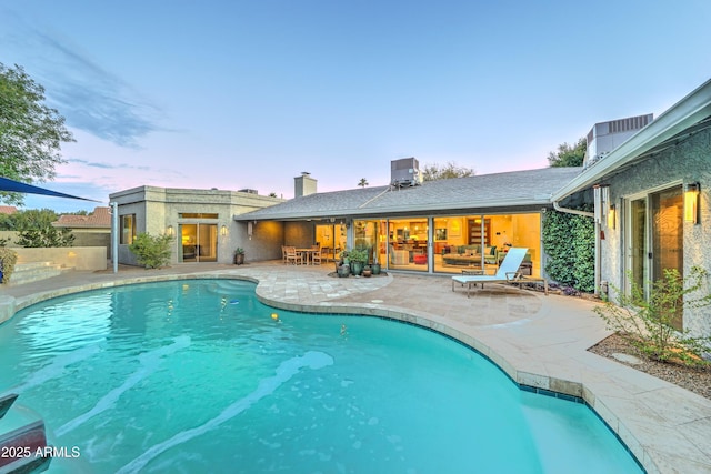 pool at dusk with a patio area and central air condition unit