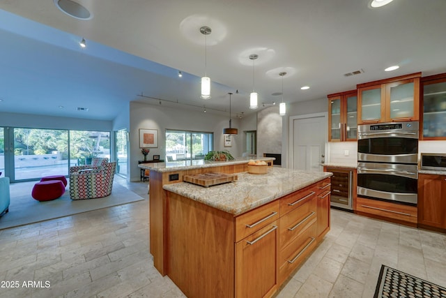 kitchen featuring hanging light fixtures, stainless steel appliances, light stone countertops, and a kitchen island