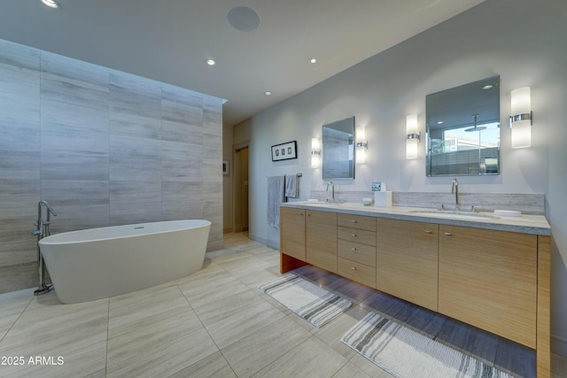 bathroom with tile patterned flooring, vanity, a tub, and tile walls