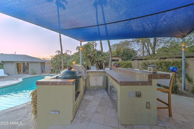 patio terrace at dusk featuring a grill, area for grilling, and a bar