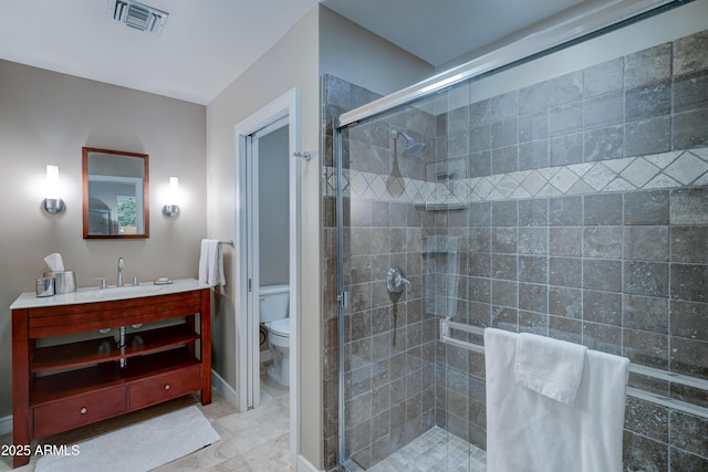 bathroom featuring vanity, a shower with shower door, and toilet