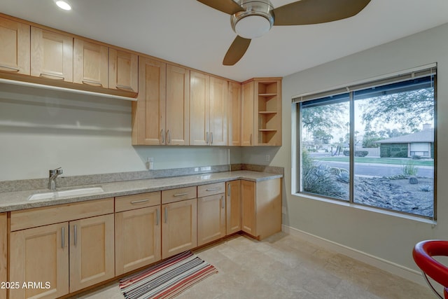 kitchen featuring light brown cabinetry, sink, light stone counters, and ceiling fan