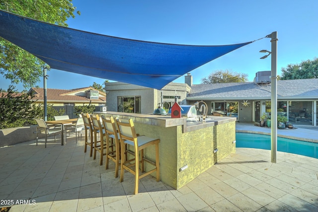 view of swimming pool featuring a patio and an outdoor bar