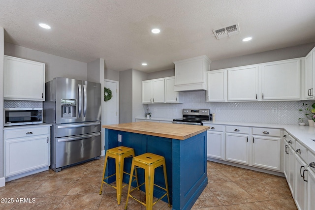3047 S Mandy St, Mesa, AZ 85212 - kitchen featuring appliances with stainless steel finishes, wood counters, a center island, backsplash, and a kitchen bar