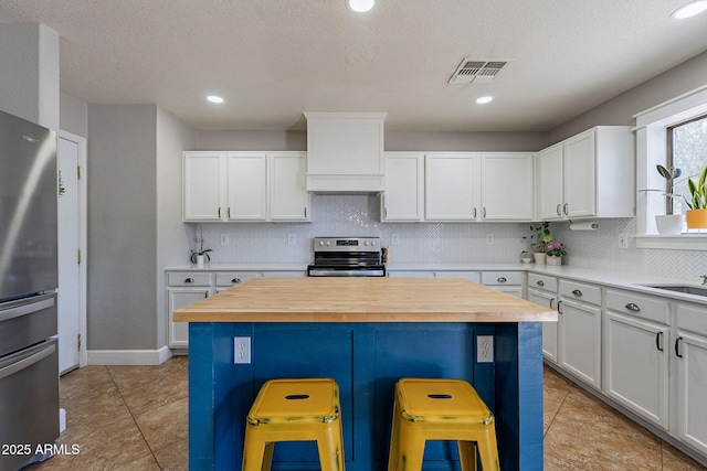 3047 S Mandy St, Mesa, AZ 85212 - kitchen featuring appliances with stainless steel finishes, premium range hood, a kitchen bar, butcher block countertops, and recessed lighting
