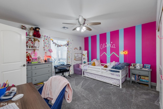 bedroom featuring an accent wall, dark colored carpet, visible vents, and ceiling fan