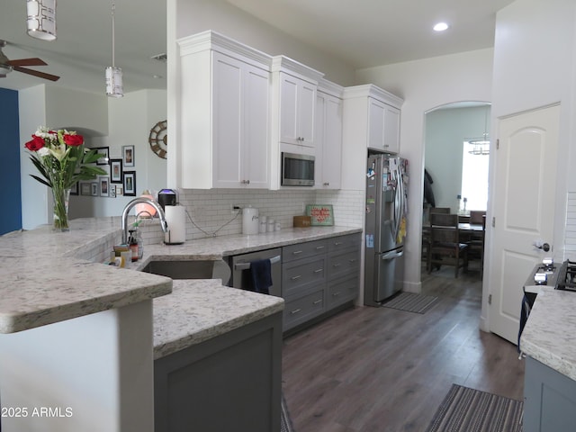 kitchen featuring a peninsula, white cabinetry, stainless steel appliances, and a sink