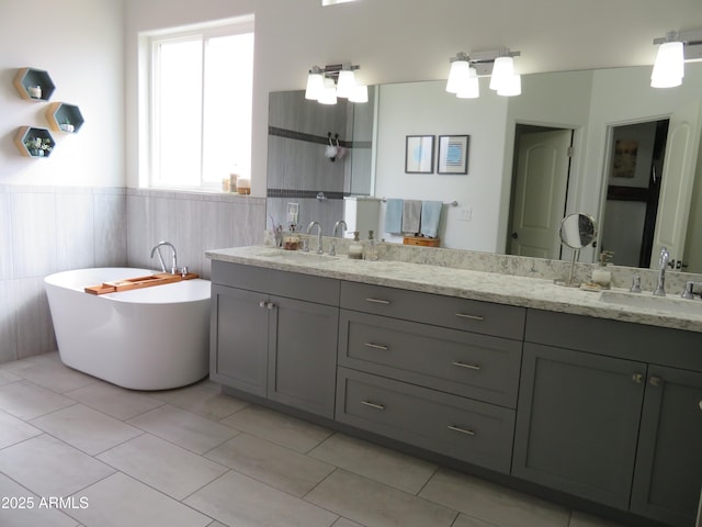 bathroom featuring double vanity, a wainscoted wall, tile walls, and a sink