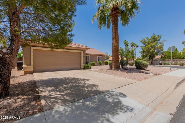 view of front of property with stucco siding, concrete driveway, a garage, fence, and a tile roof