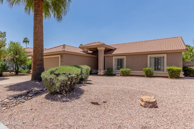 mediterranean / spanish-style house featuring a tiled roof, stucco siding, and an attached garage
