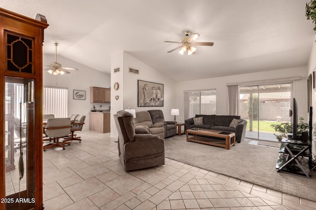 living area featuring a ceiling fan, vaulted ceiling, light tile patterned floors, and light carpet