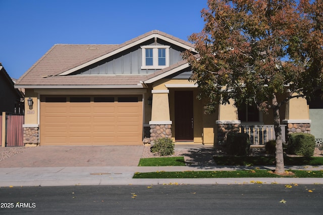 craftsman-style home featuring a garage, a tile roof, stone siding, decorative driveway, and board and batten siding