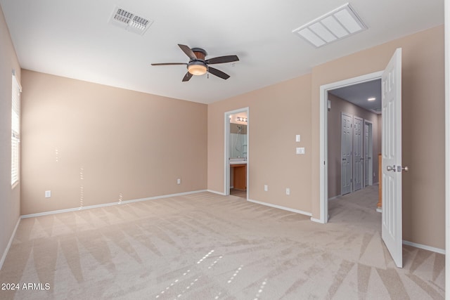 unfurnished bedroom featuring ceiling fan, ensuite bathroom, and light colored carpet