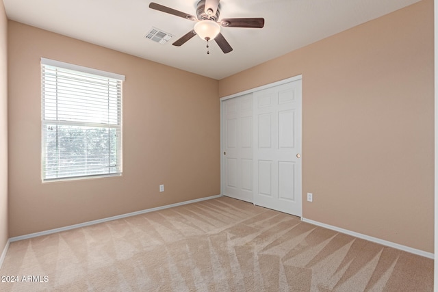 unfurnished bedroom with light carpet, multiple windows, a closet, and ceiling fan