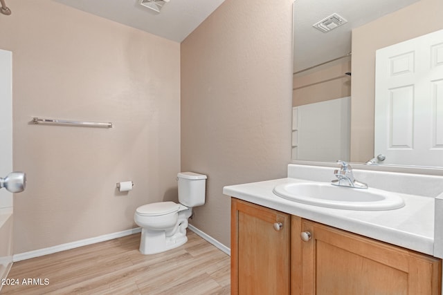 bathroom with vanity, toilet, hardwood / wood-style flooring, and a shower