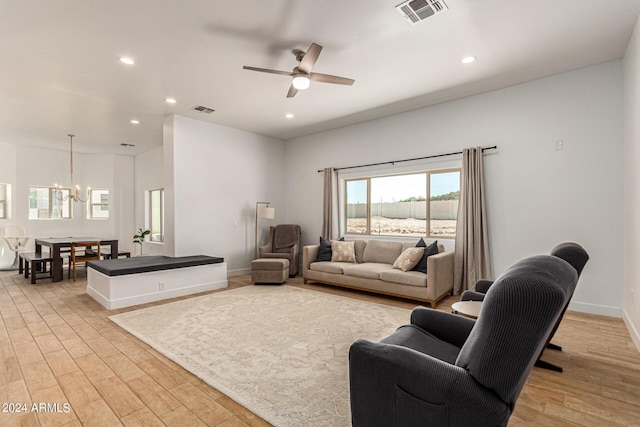 living room with ceiling fan with notable chandelier and light hardwood / wood-style floors