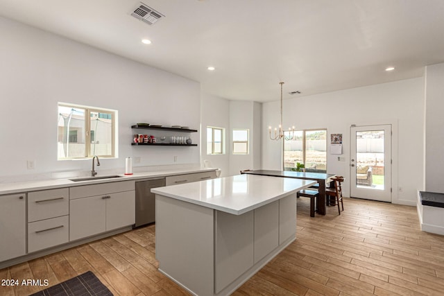 kitchen featuring sink, a center island, hanging light fixtures, stainless steel dishwasher, and light hardwood / wood-style floors