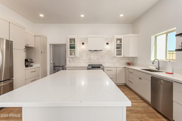 kitchen with white cabinetry, appliances with stainless steel finishes, a center island, and sink