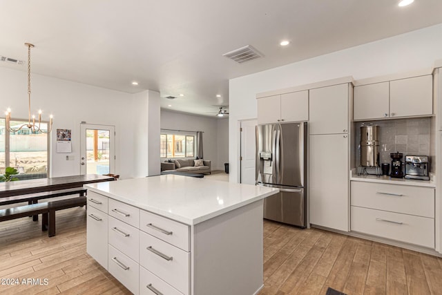 kitchen with stainless steel refrigerator with ice dispenser, a kitchen island, white cabinets, and light hardwood / wood-style flooring