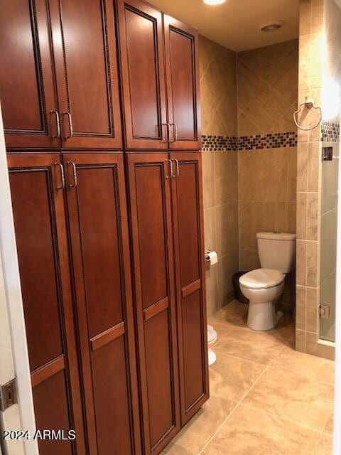 bathroom featuring tile patterned floors, tile walls, and toilet