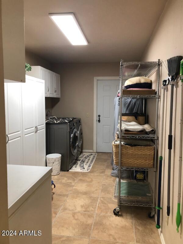 clothes washing area with washer and clothes dryer and cabinets