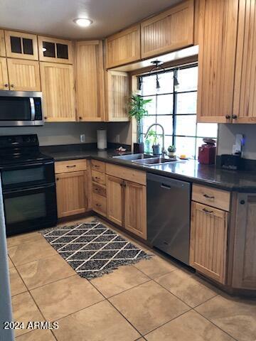 kitchen with black appliances, light tile patterned floors, and sink