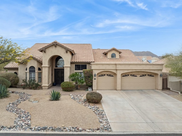 mediterranean / spanish house featuring a tile roof, driveway, an attached garage, and stucco siding