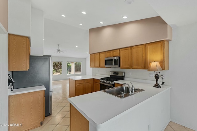 kitchen featuring light tile patterned floors, a peninsula, stainless steel appliances, light countertops, and a sink