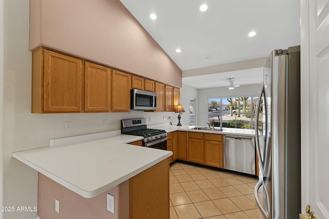 kitchen featuring lofted ceiling, a peninsula, stainless steel appliances, light countertops, and a sink