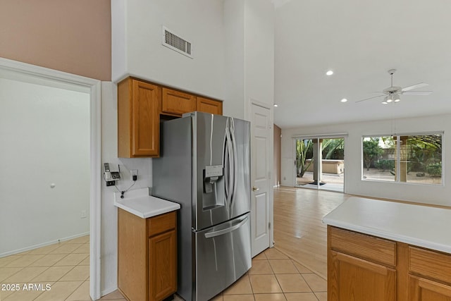 kitchen with brown cabinets, light tile patterned floors, light countertops, visible vents, and stainless steel fridge with ice dispenser