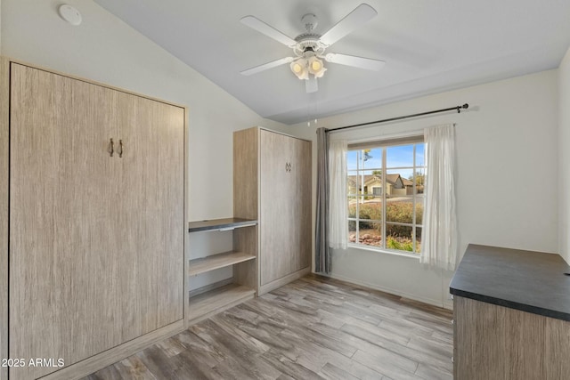 unfurnished bedroom with lofted ceiling, light wood finished floors, a ceiling fan, and baseboards