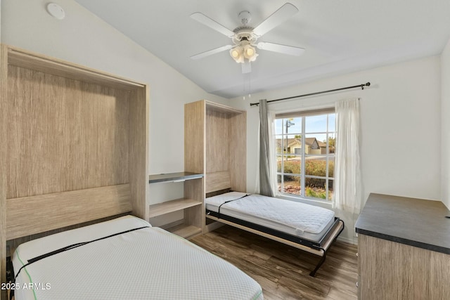 bedroom with a ceiling fan, vaulted ceiling, and wood finished floors